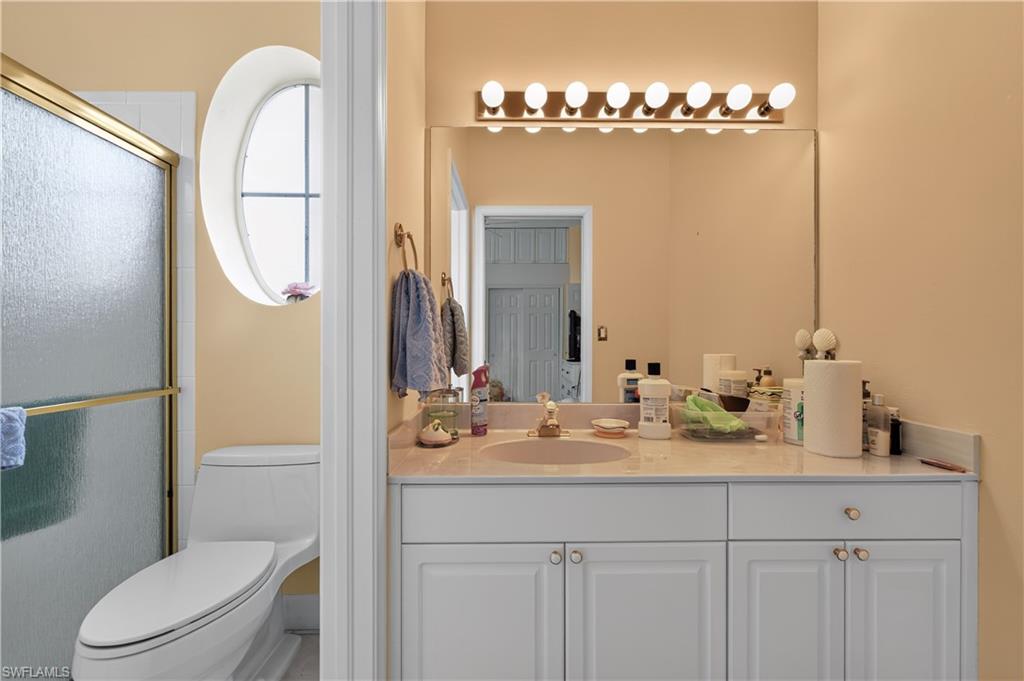 Bathroom featuring a white vanity with a light-toned countertop, a large wall-mounted mirror, and a multi-bulb vanity light fixture