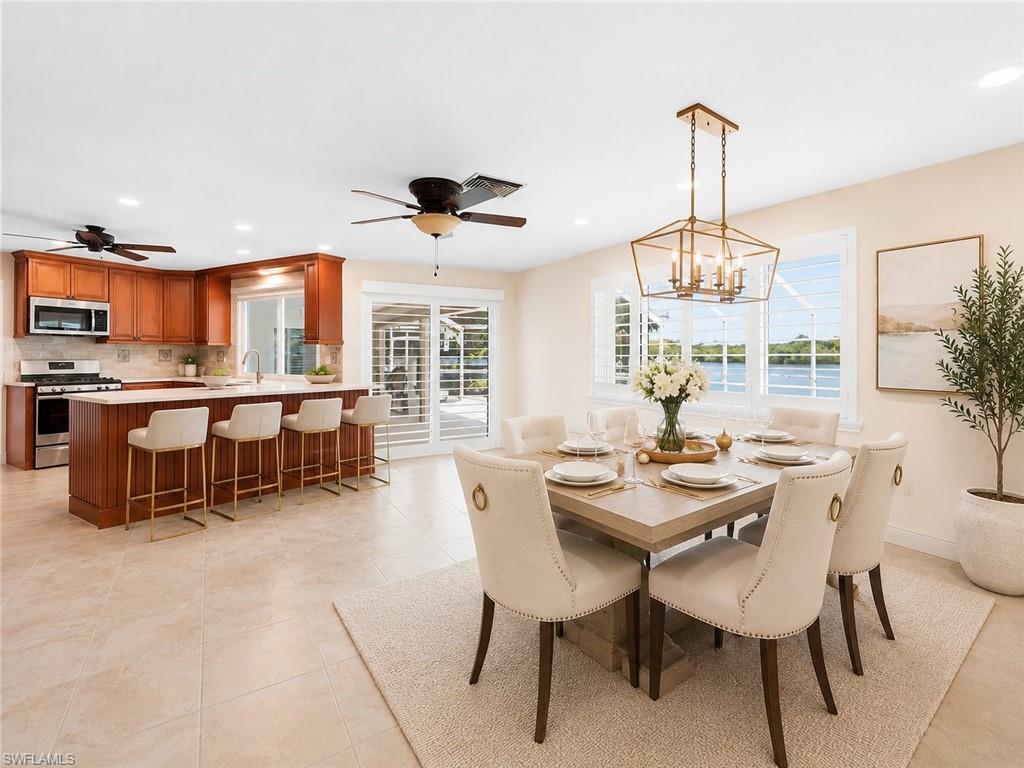 Open-concept dining area with waterscape, featuring a contemporary chandelier and plantation shutters