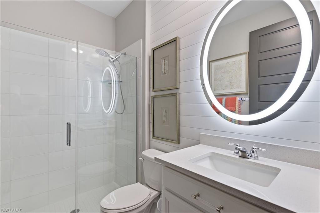Stylish guest bath featuring a backlit mirror and glass enclosed shower
