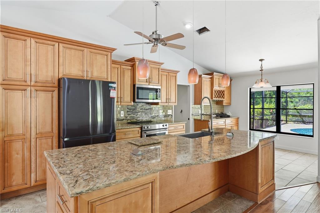 Kitchen featuring light wood cabinetry and a large island with a stone countertop