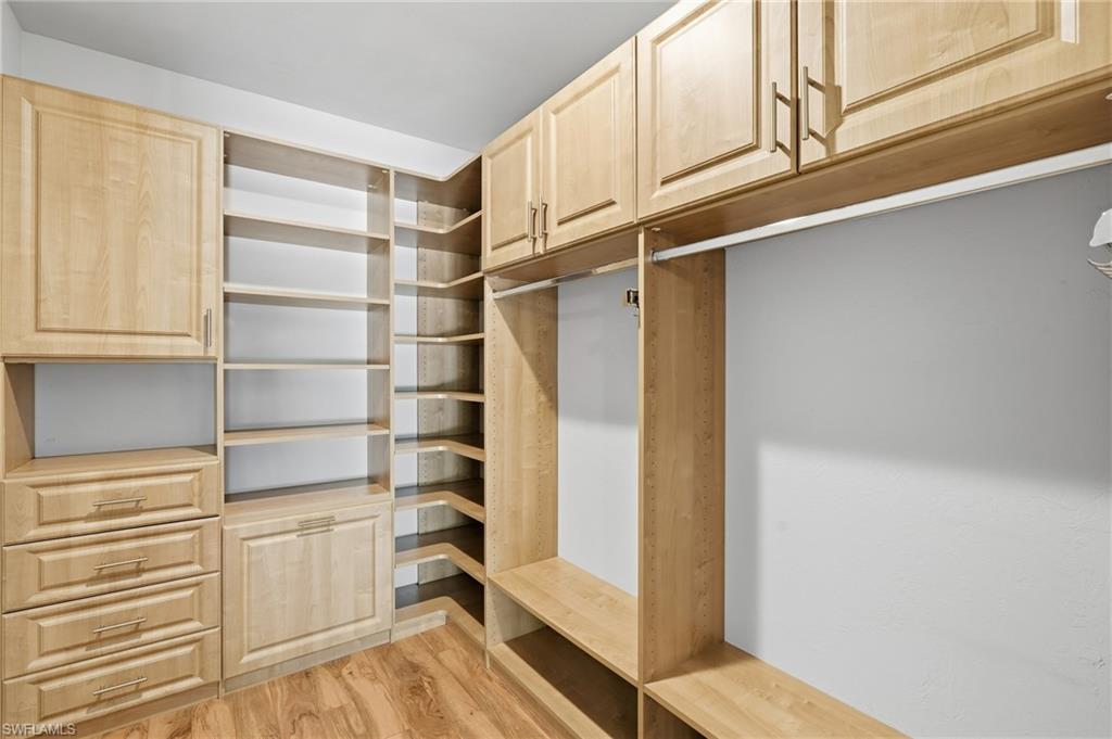 Custom-built closet system featuring light wood cabinetry, integrated shelving, multiple drawers, and hanging rods