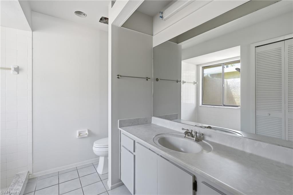 Bathroom featuring a vanity with an integrated sink, laminate countertop, and a large wall-mounted mirror