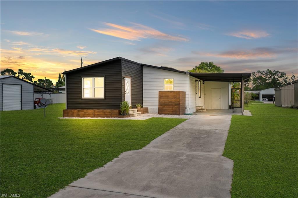 Modern exterior featuring black and white siding, an attached carport, and a concrete driveway