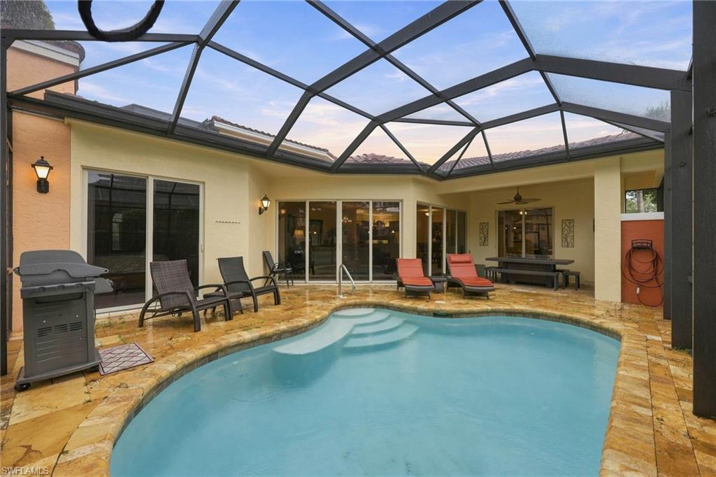 Screened pool enclosure featuring a resort-style swimming pool with turquoise water, wood-finish decking, and abundant natural light from the polycarbonate roof panels