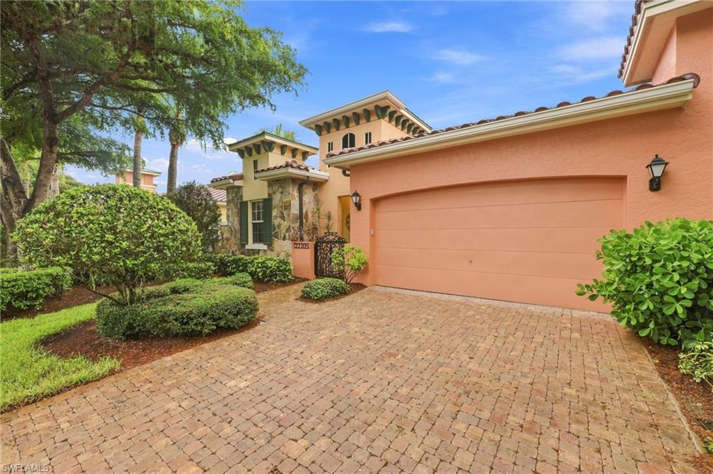 Mediterranean-inspired exterior featuring a paver driveway, terracotta-toned stucco, tile roof, and integrated garage