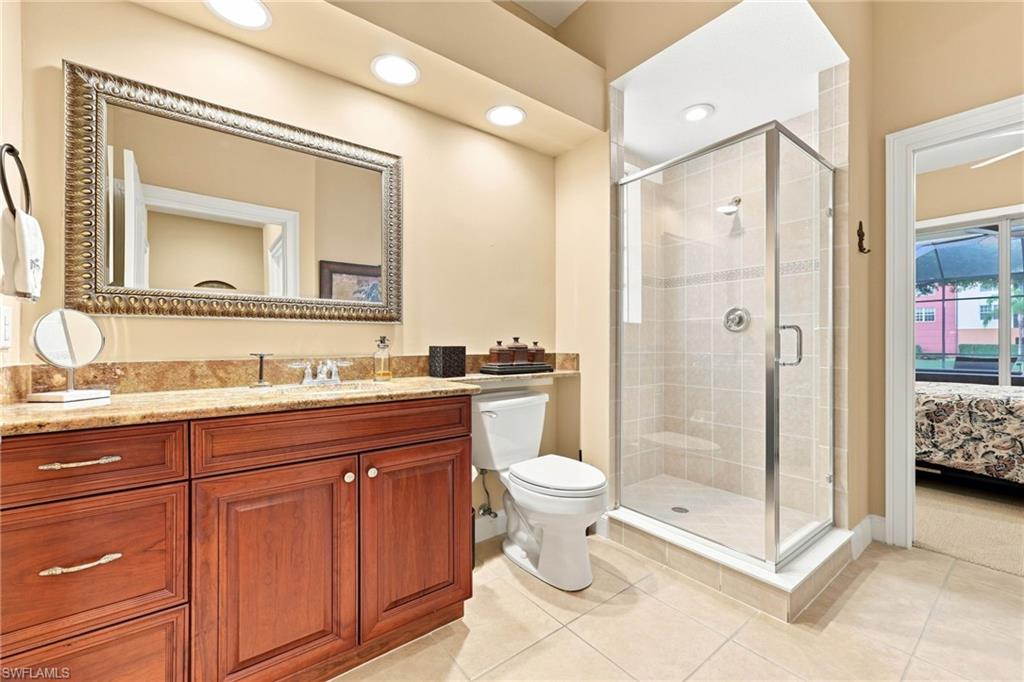 Spa-inspired primary bathroom featuring a wood-finish vanity with dual sinks, granite countertop, and polished chrome hardware