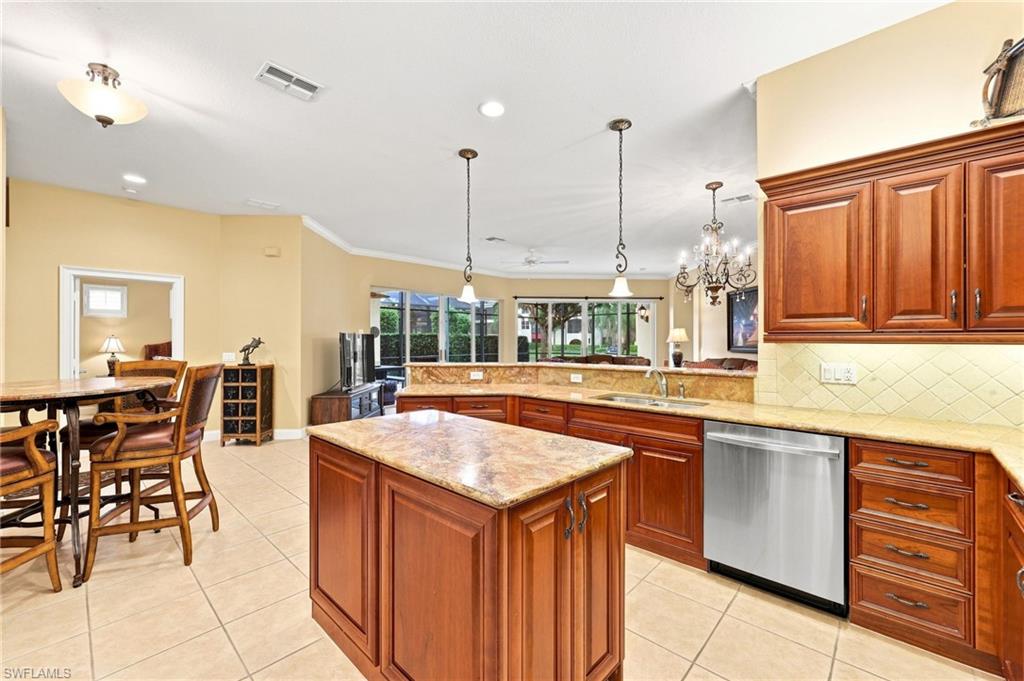 Expansive kitchen featuring a central island, wood-finish cabinetry, granite countertops, stainless steel appliances, and tile flooring