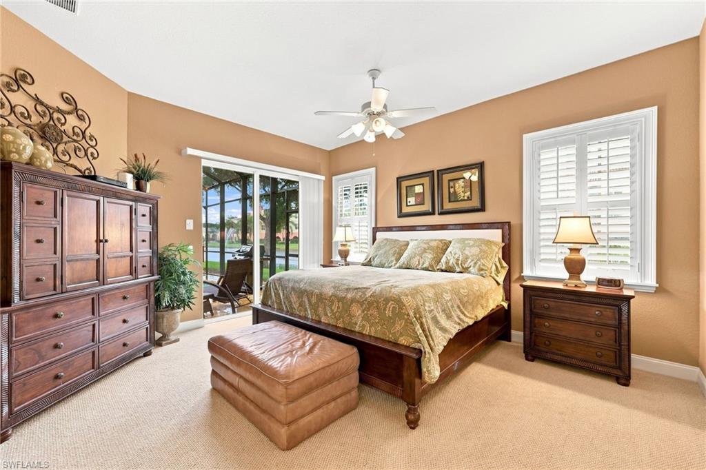 Spacious bedroom featuring neutral carpeting, a vaulted ceiling with a ceiling fan, and direct access to an outdoor screened patio area