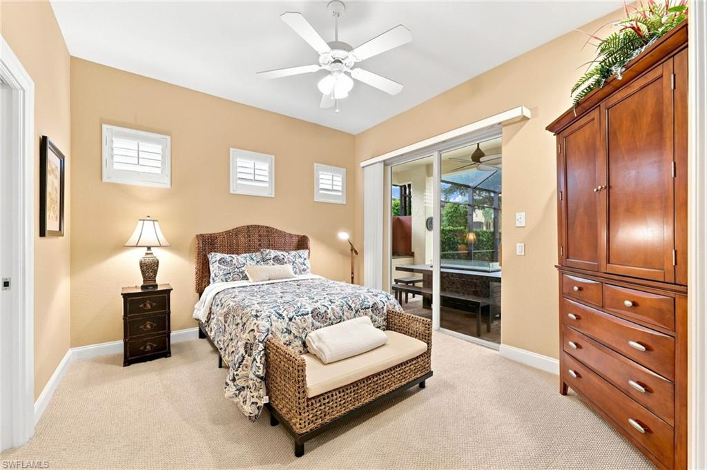 Spacious primary bedroom featuring warm neutral walls, abundant natural light from multiple windows, ceiling fan with integrated lighting, wood-finish flooring, and direct access to an ensuite bathroom