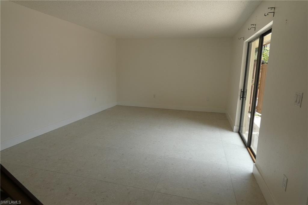 Spacious room featuring tile flooring, white baseboards, and a sliding glass door with black framing and hardware