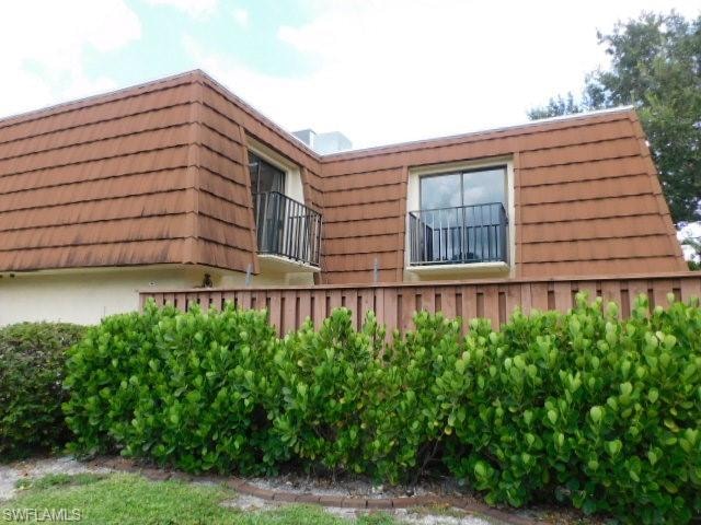 Exterior featuring a brown tiled mansard roof, two dormer windows with sliding glass, and black metal balcony railings