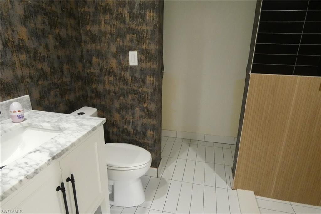 Vanity with a marble countertop and undermount sink, complemented by white cabinetry and black hardware