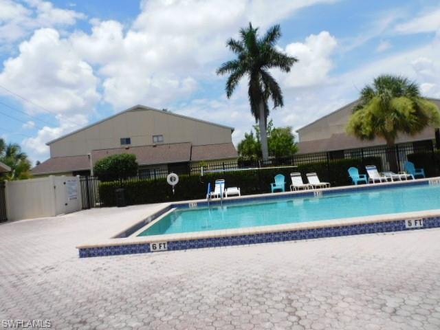 Outdoor swimming pool featuring a tiled edge and a paver deck