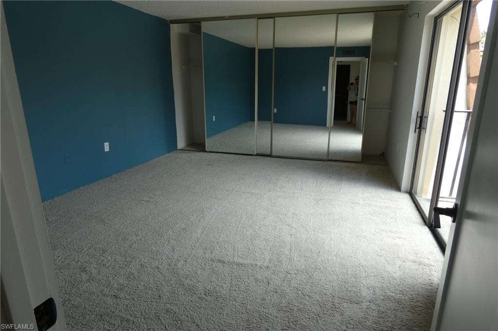 Carpeted room with a blue accent wall and mirrored sliding closet doors