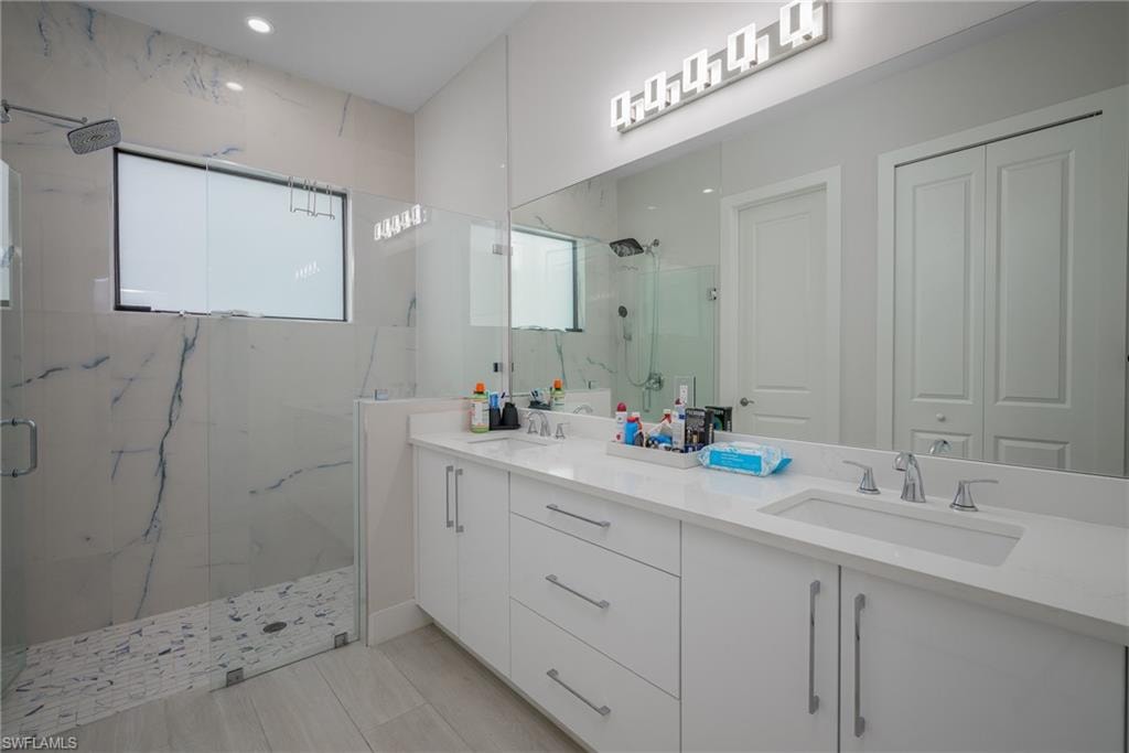 Bathroom featuring a spacious walk-in shower with large format veined tile, a mosaic tile shower floor, and a rectangular window