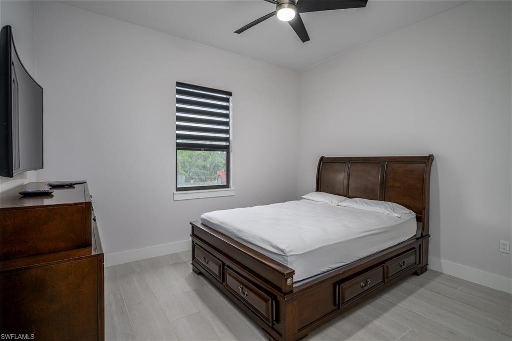 Light gray walls with white trim, wood-finish flooring, and a ceiling fan with integrated lighting