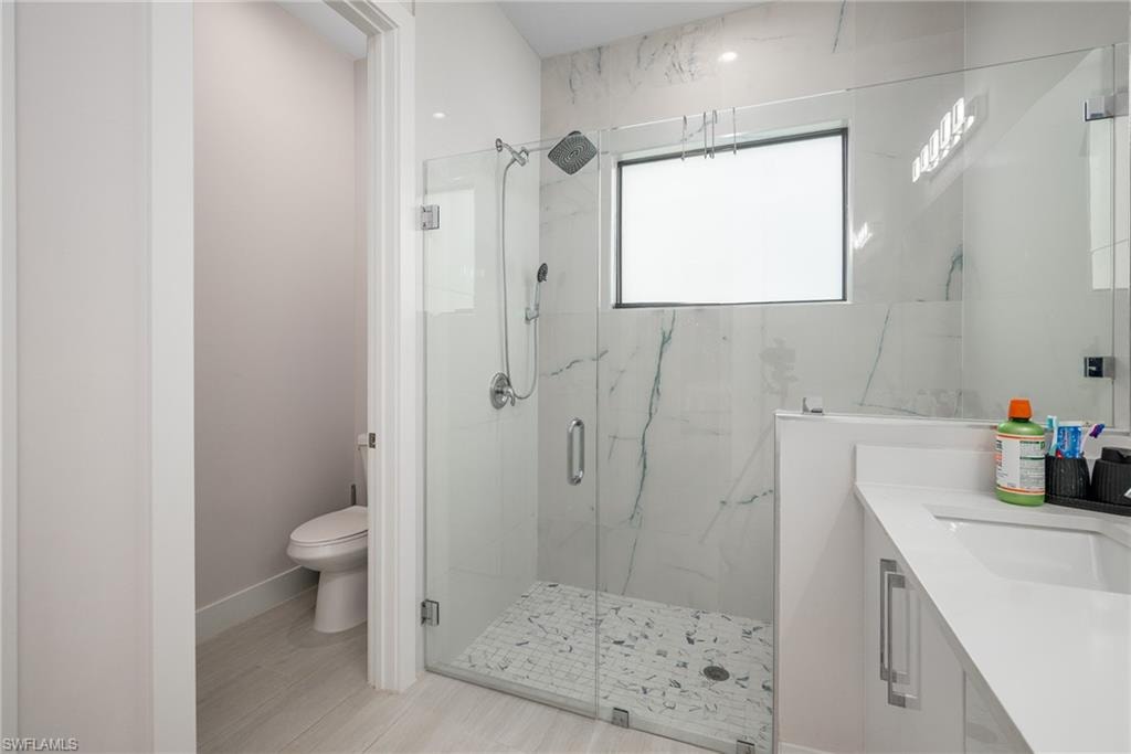 Contemporary bathroom featuring a frameless glass shower enclosure with marble-patterned tile surround and mosaic tile flooring