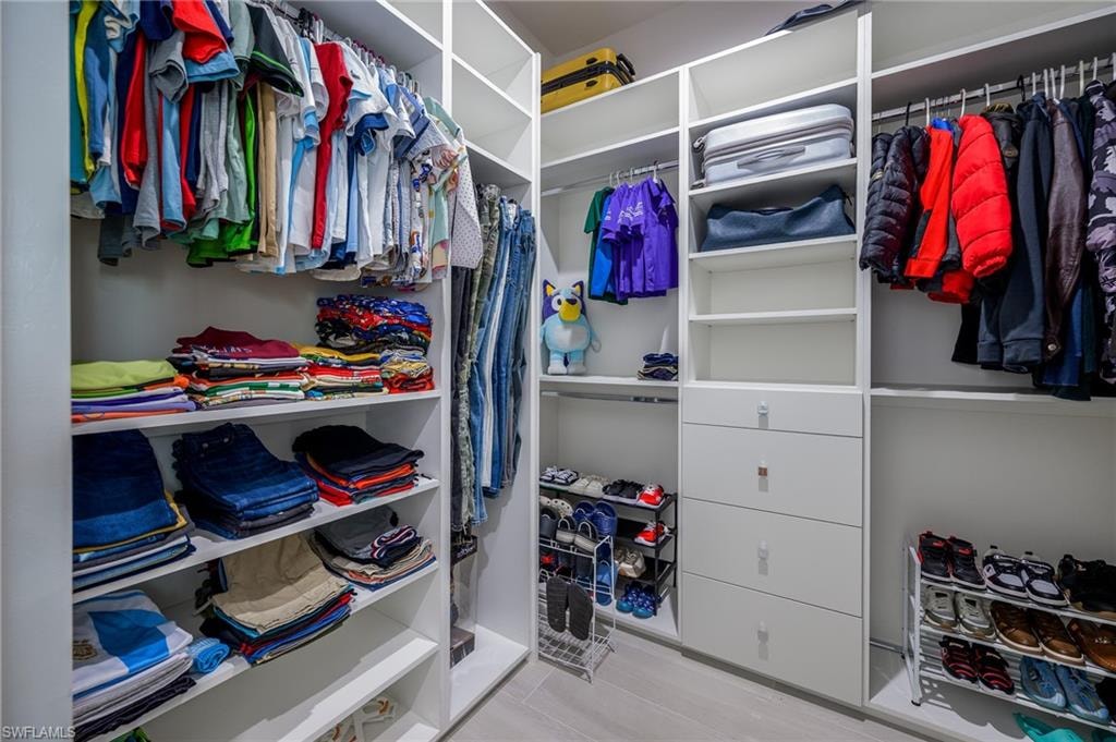 Customizable white built-in closet system featuring multiple hanging rods, adjustable shelving, and integrated drawer storage