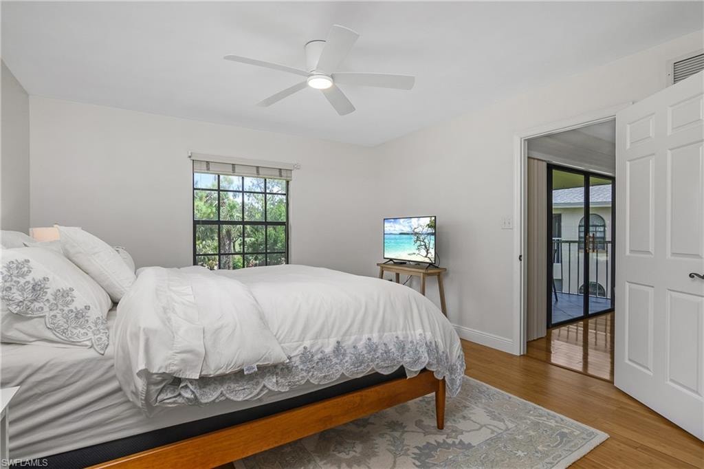 Primary Bedroom with wood finished floors, multiple windows, and a ceiling fan, tv and queen size bed