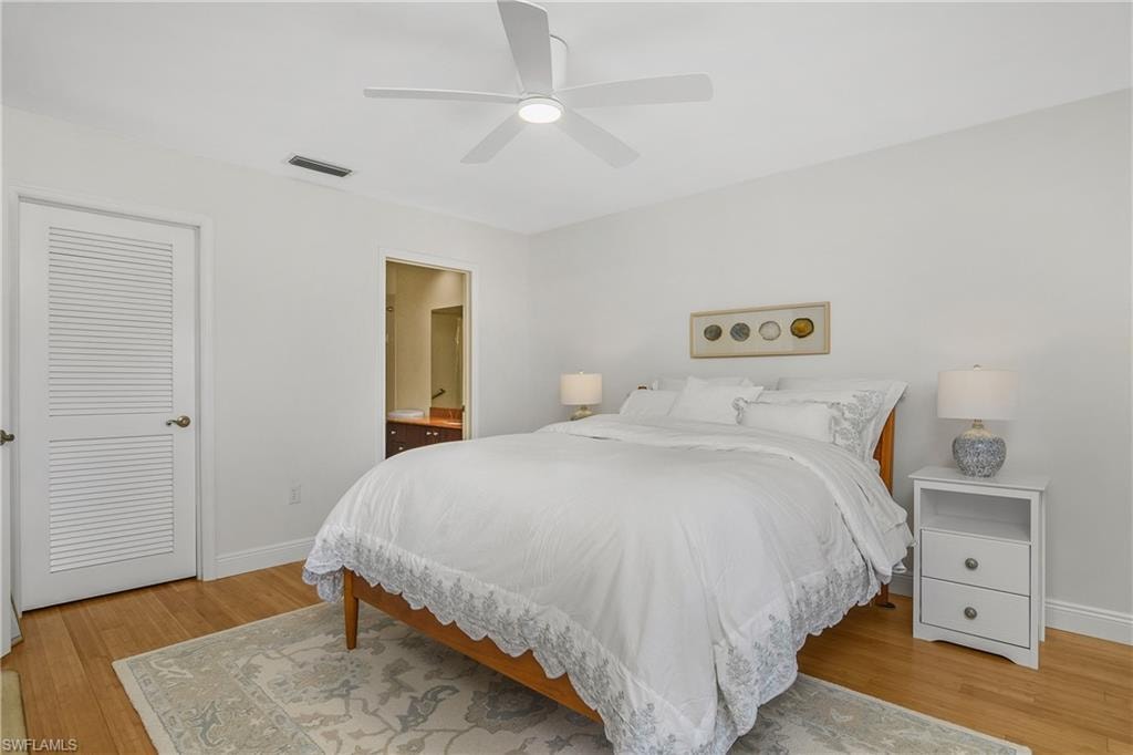 Bedroom featuring wood finished floors, ceiling fan, and ensuite bath