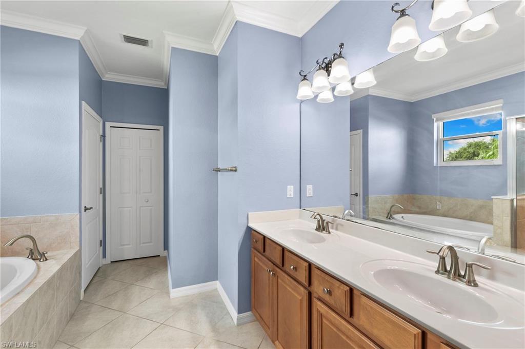 Primary ensuite bath with dual vanities, garden tub, and walk in shower.