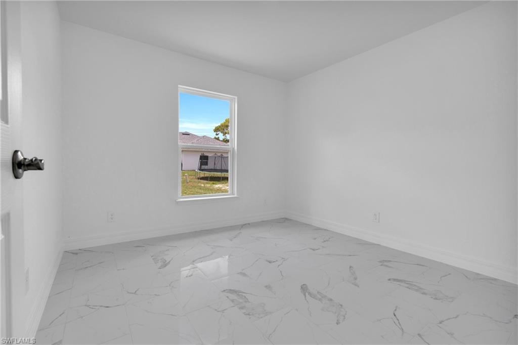 Bright interior space featuring large format tile flooring, white walls, white trim, and a single window with a white frame