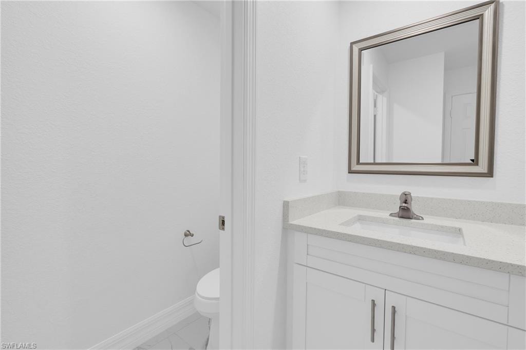 Vanity with a light-toned countertop, an integrated rectangular sink, and a framed mirror