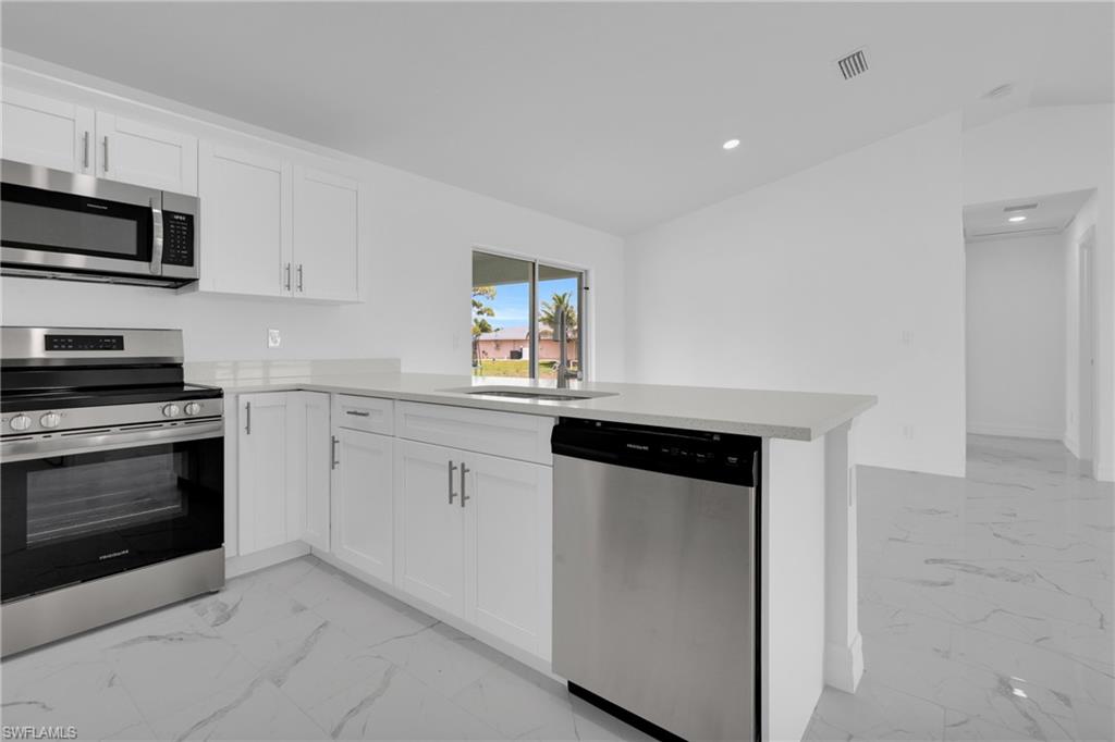 Modern kitchen featuring white shaker cabinetry, stainless steel appliances, and light-toned countertops