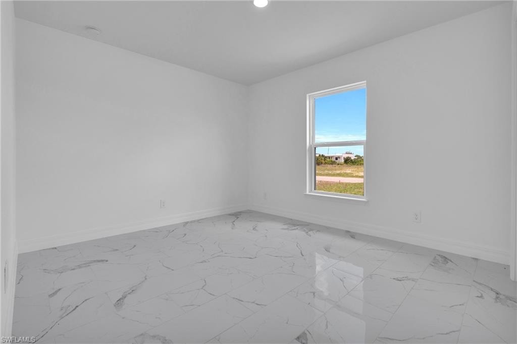 Spacious room featuring large format tile flooring, crisp white walls, and a prominent window
