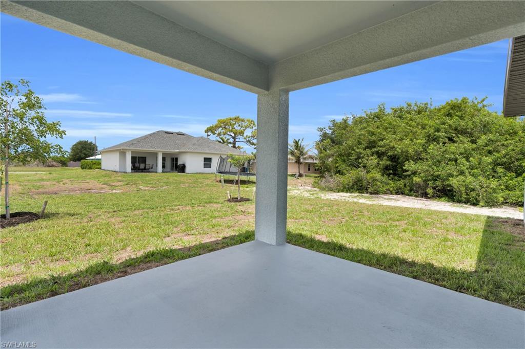 Expansive rear yard with a covered patio featuring a concrete surface