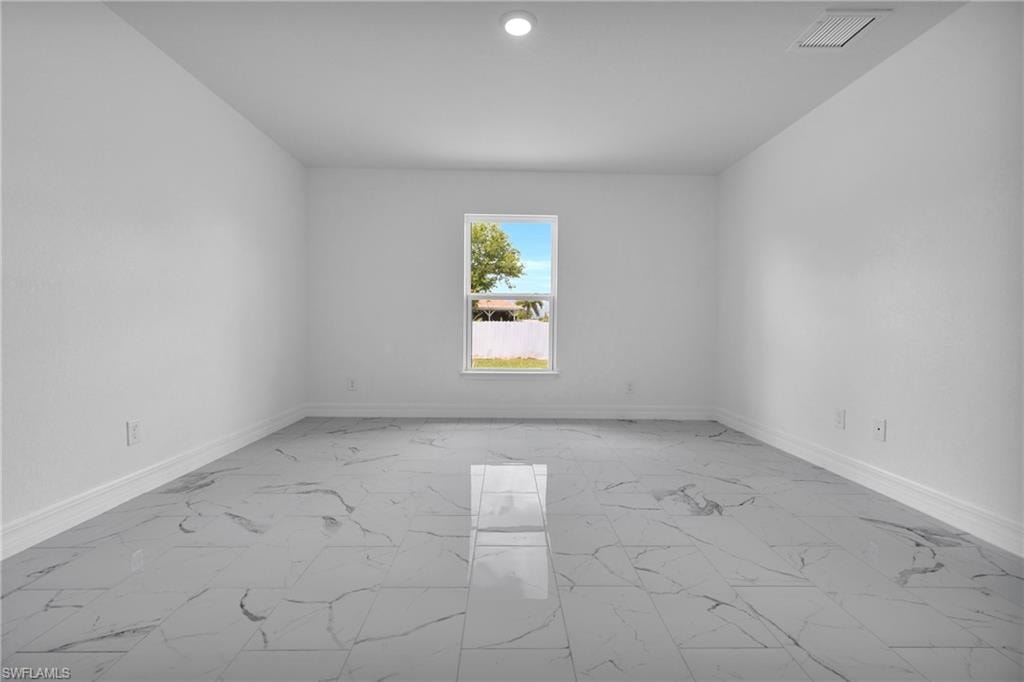 Spacious room featuring large format marble-look tile flooring, white baseboards, and a single window