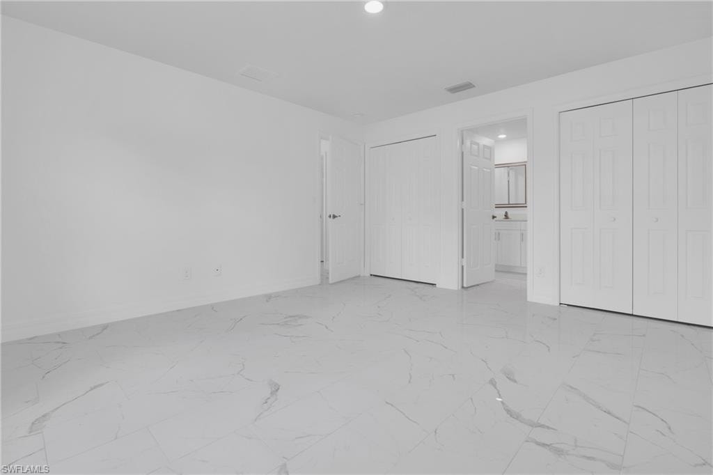 Spacious room featuring white walls and large format tile flooring