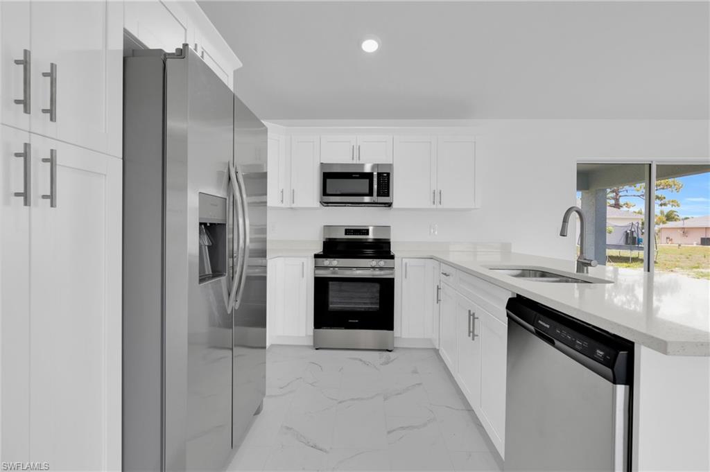 Contemporary kitchen featuring white shaker cabinetry, stainless steel appliances, light countertops, and wood-finish flooring