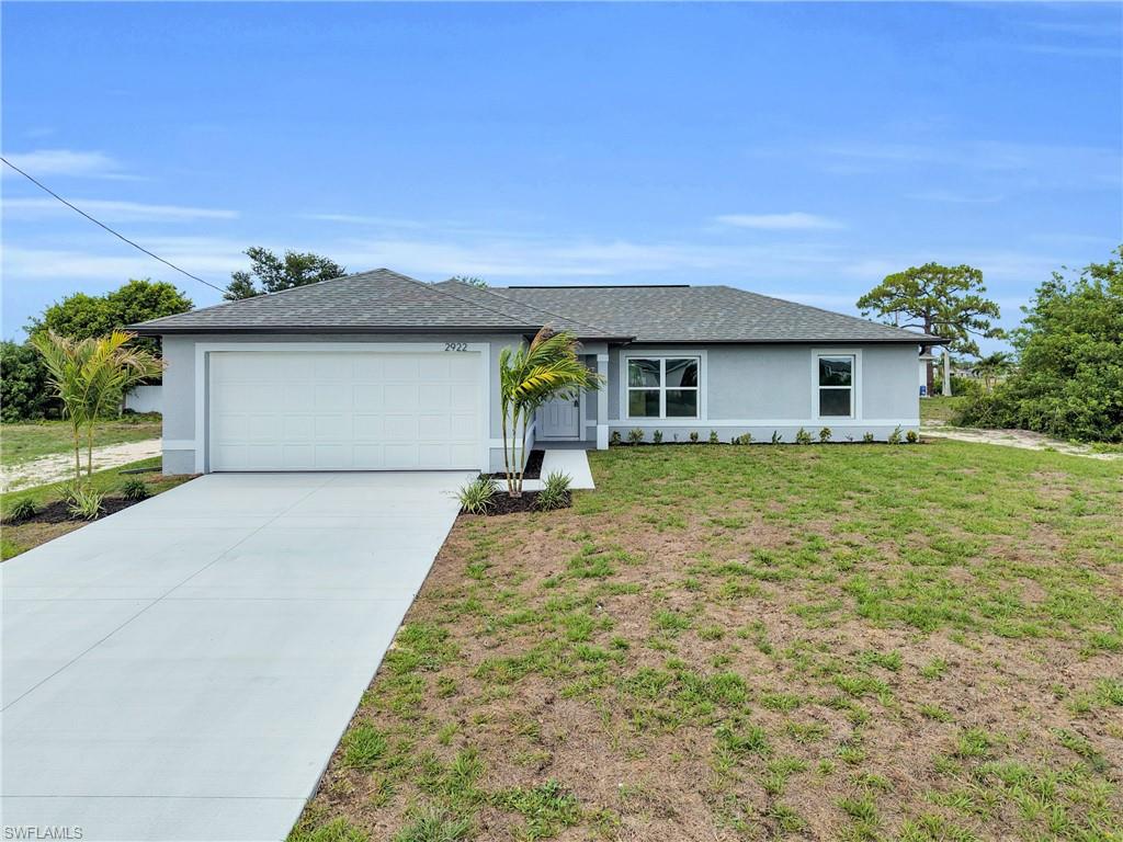 Contemporary single-story residence featuring a two-car garage, light gray exterior siding, and a dark shingle roof
