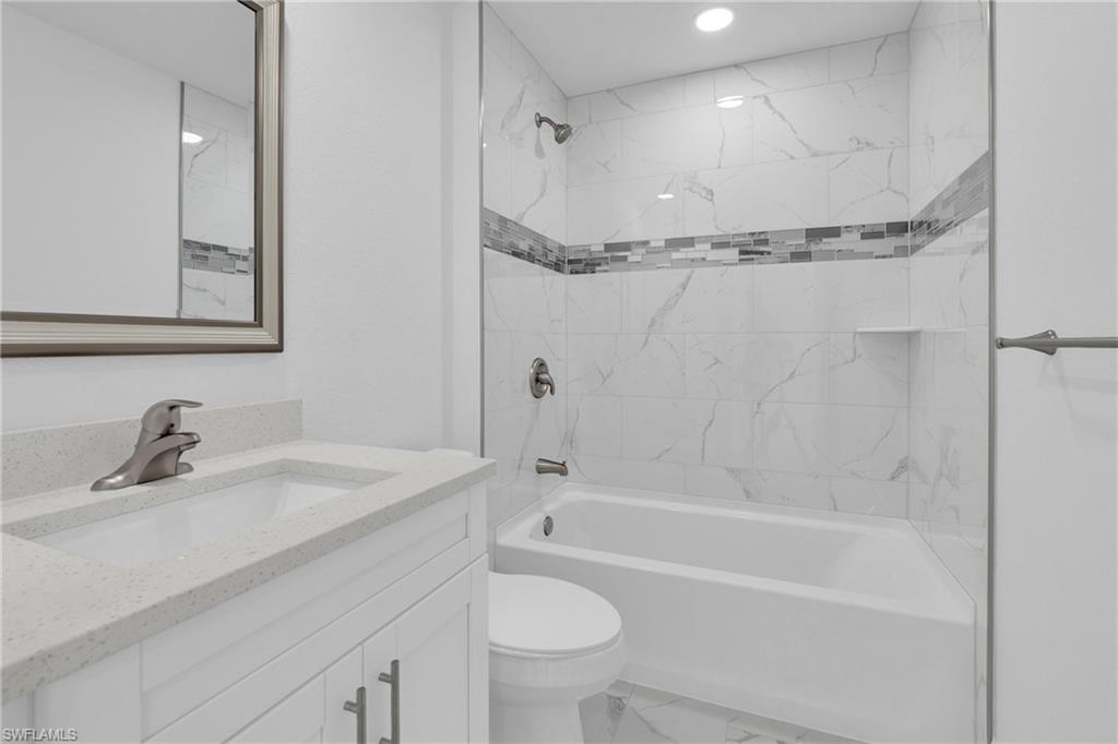 Bathroom featuring a single vanity with a light-toned countertop, an undermount sink, and a framed mirror