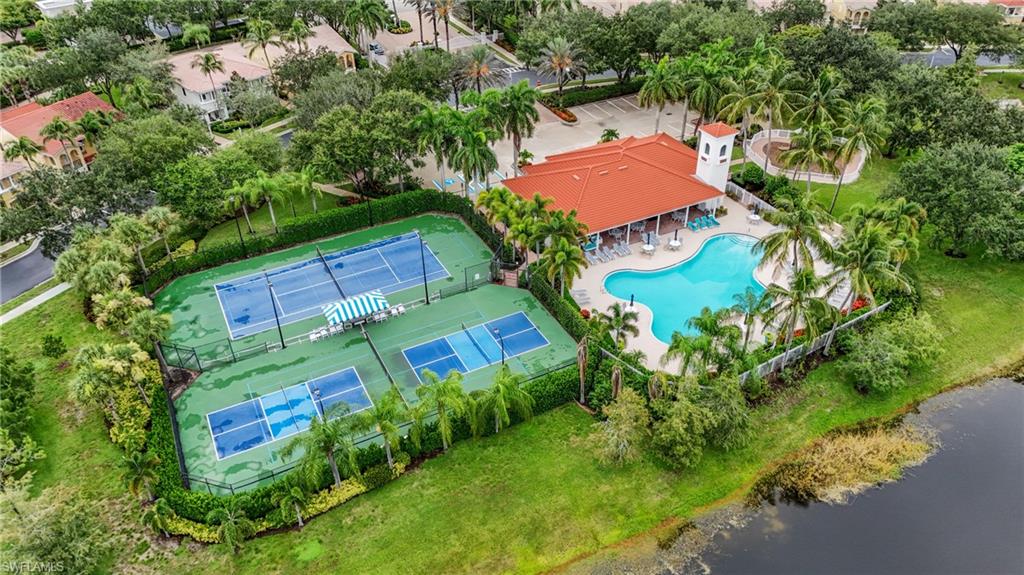 Recreational area featuring two tennis courts, two pickleball courts, a central swimming pool with a surrounding patio, and an adjacent clubhouse with a red tile roof