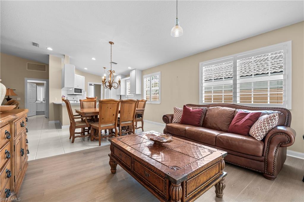 Open-concept living space featuring wood-finish flooring transitioning to tile