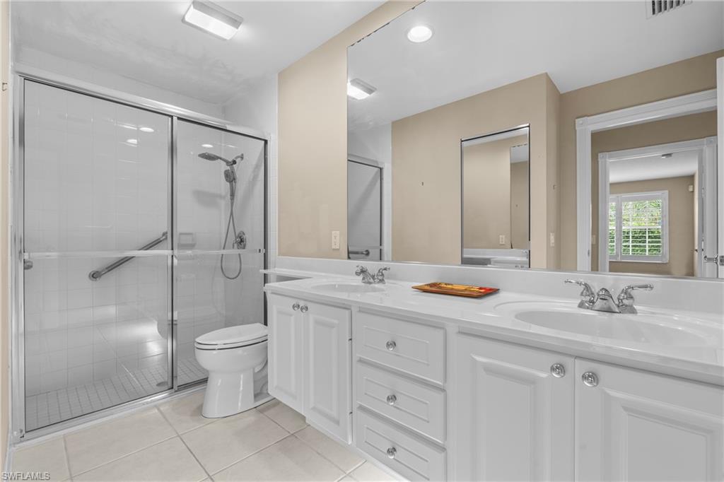 Bathroom featuring a dual vanity with white cabinetry, integrated sinks, and chrome fixtures
