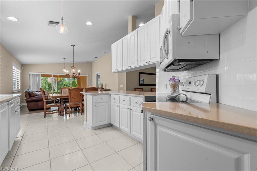 Kitchen featuring white cabinetry, light-toned countertops, white tile backsplash, and tile flooring