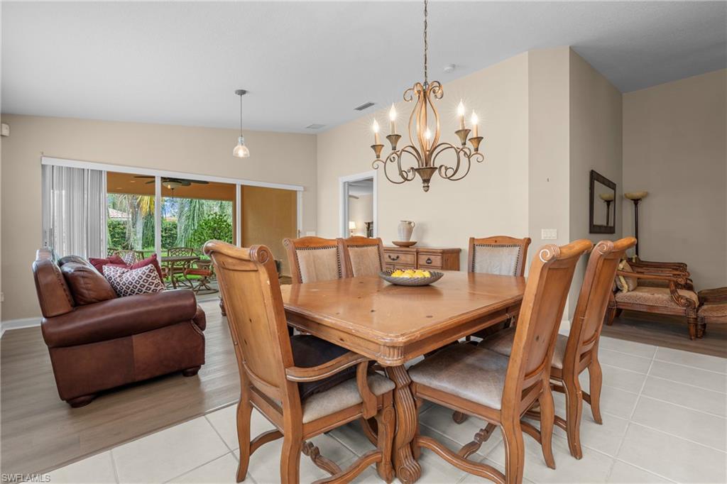 Spacious dining area featuring a decorative chandelier, ample natural light, tile flooring, and direct access to an outdoor patio