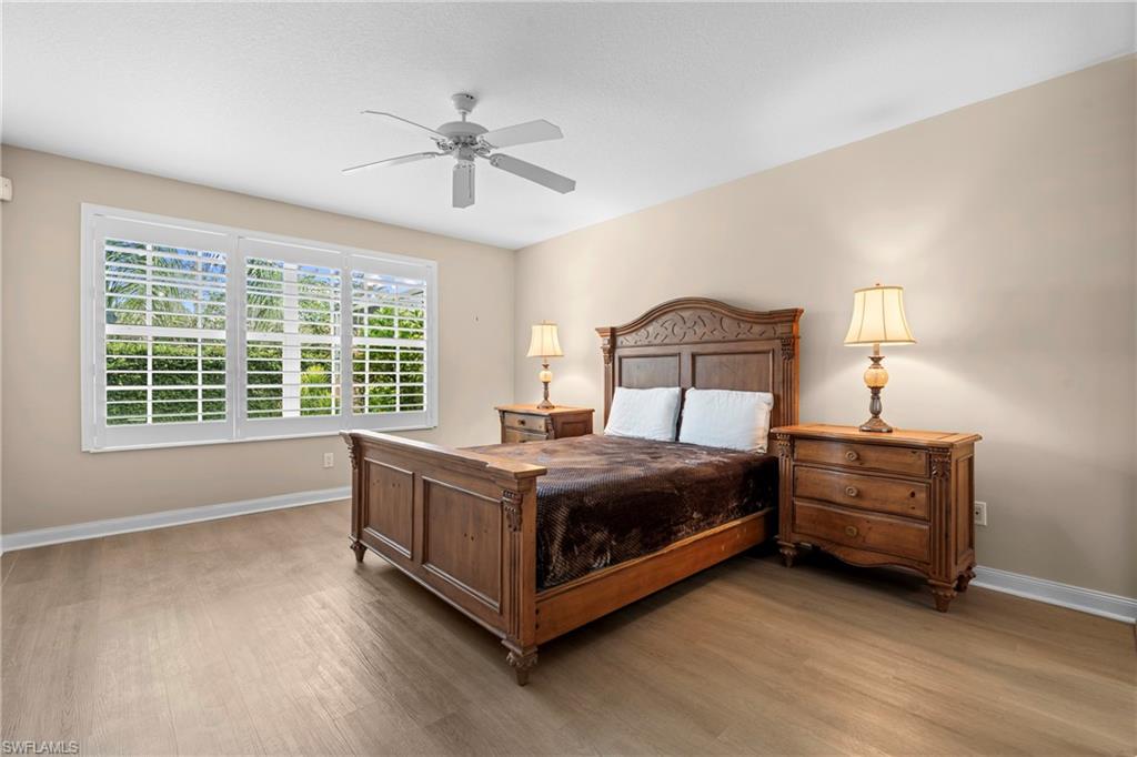 Spacious room featuring light wood-finish flooring, a ceiling fan, and three windows with white plantation shutters