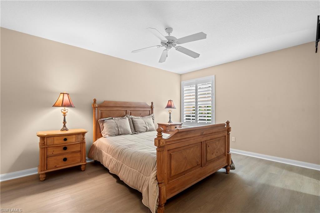 Bedroom featuring wood-finish flooring, a neutral color palette, and a window with white plantation shutters