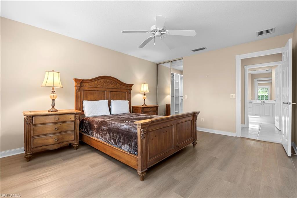 Spacious room featuring wood-finish flooring, a ceiling fan, and access to a closet with sliding mirrored doors
