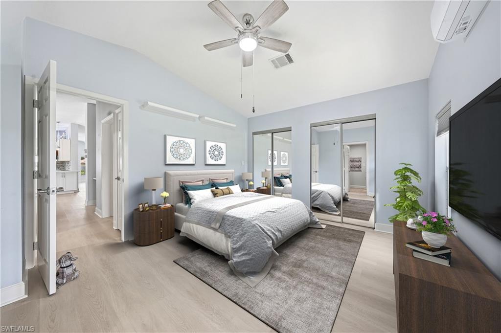 Vaulted ceiling with a ceiling fan and recessed lighting, wood-finish flooring, mirrored closet doors, and light blue wall tones