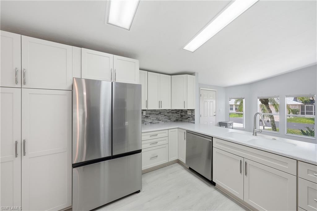 Modern kitchen featuring white shaker cabinetry, stainless steel appliances, a mosaic tile backsplash, and light-toned countertops