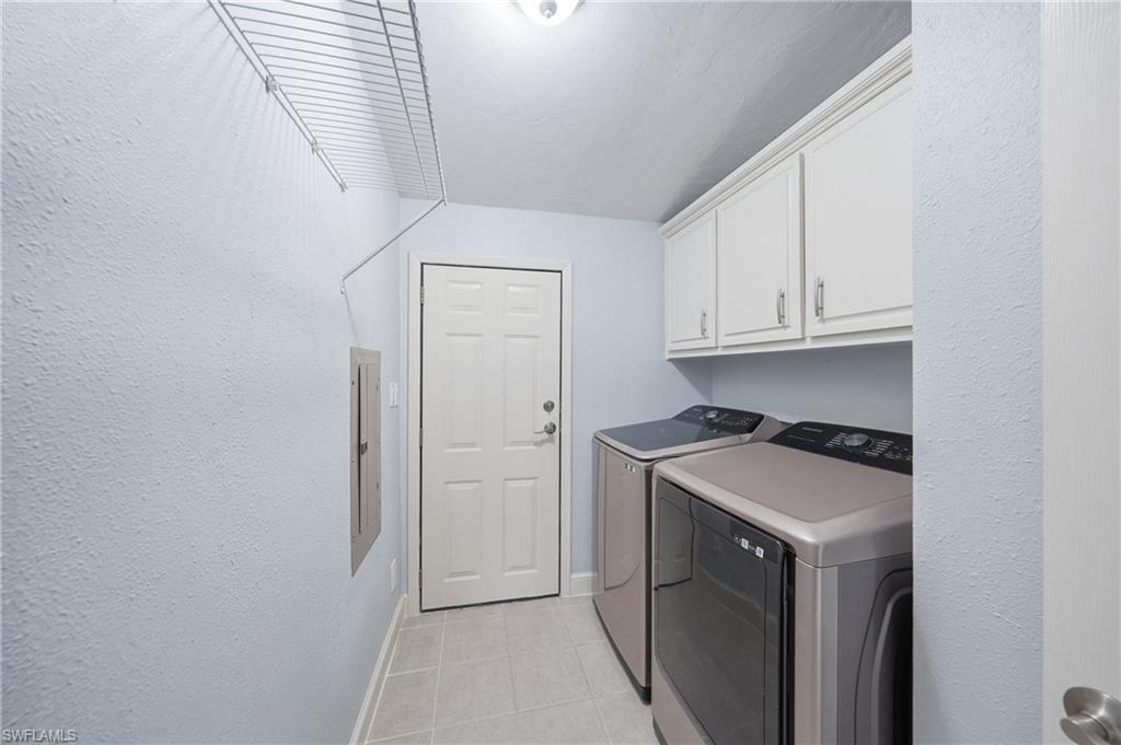Laundry area featuring upper cabinetry with brushed nickel hardware, light blue painted walls, and tile flooring