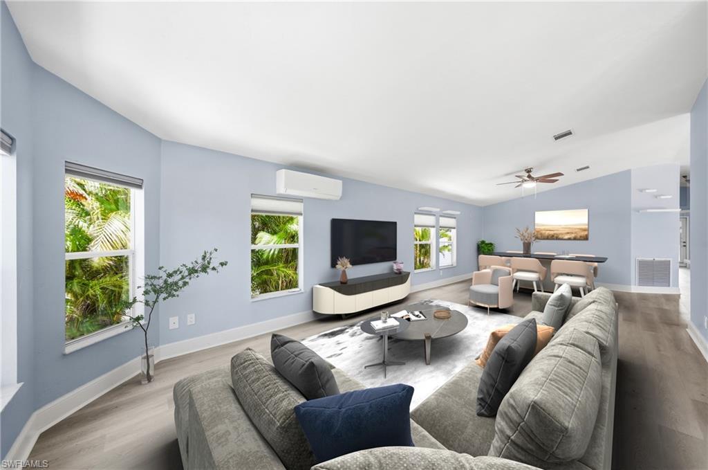 Spacious living area featuring light wood-finish flooring, vaulted ceilings, and light blue wall tones