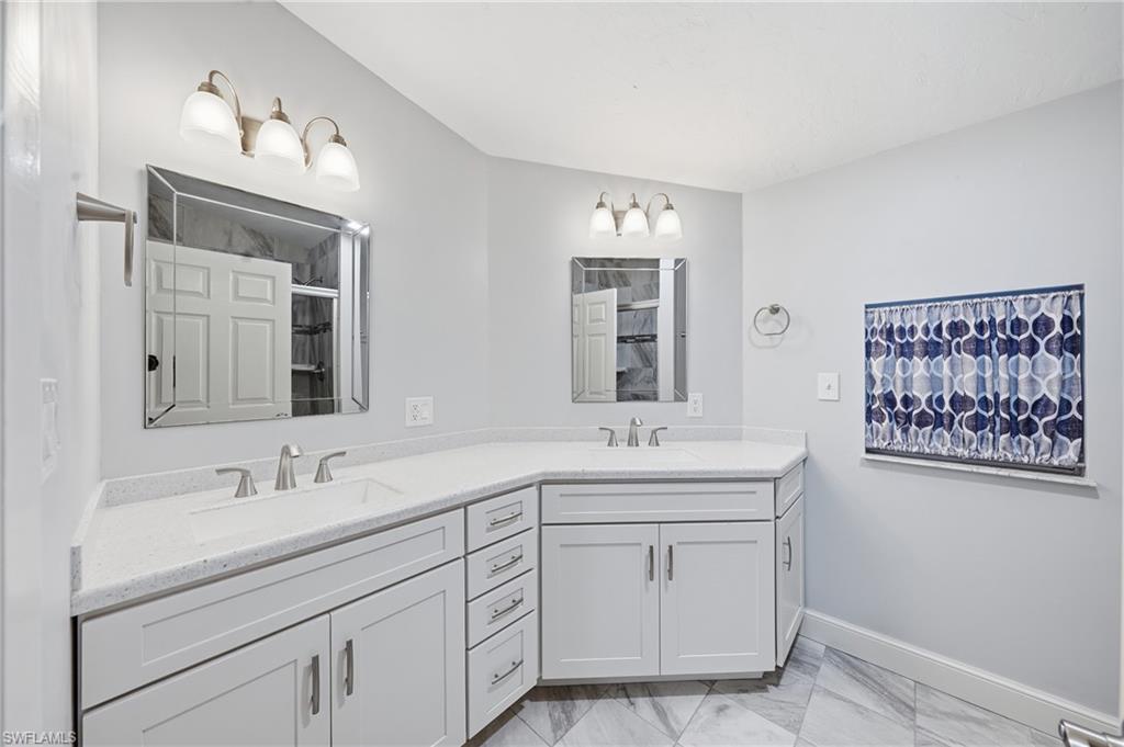 Dual vanity with white shaker cabinetry, light-toned countertops, and two framed medicine cabinets