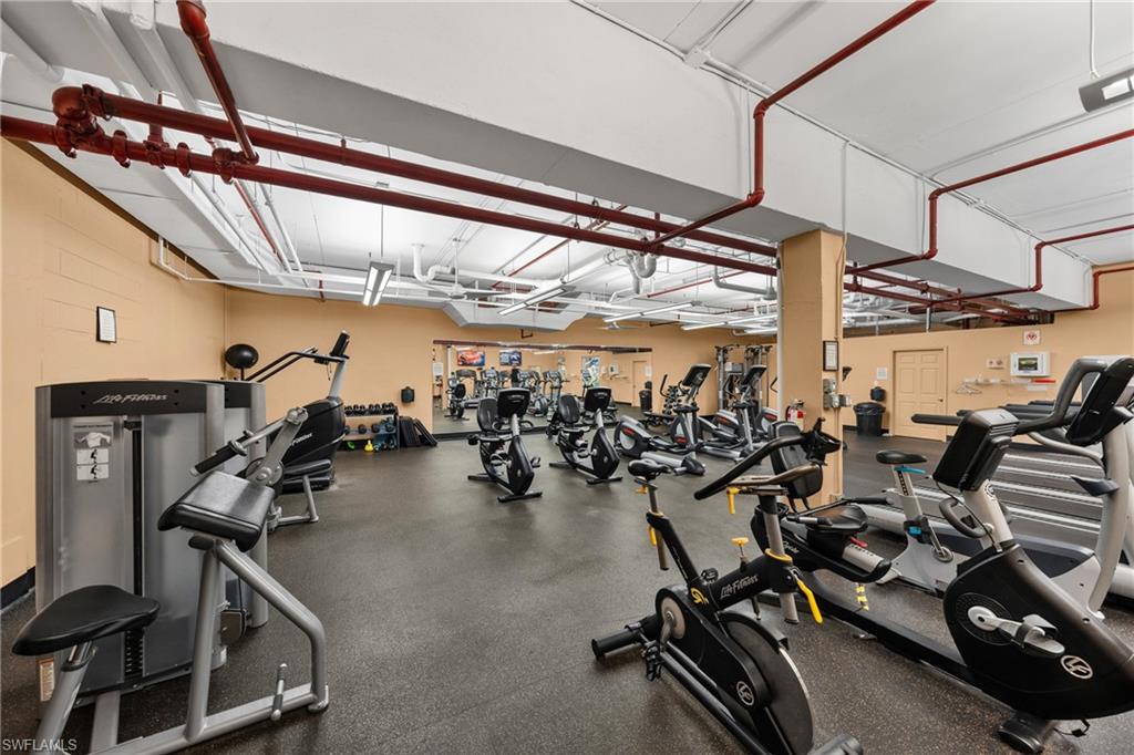 State-of-the-art fitness facility featuring multiple stationary bikes with individual console displays, professional-grade cardio equipment, and a spacious layout with high ceilings and industrial-style ductwork