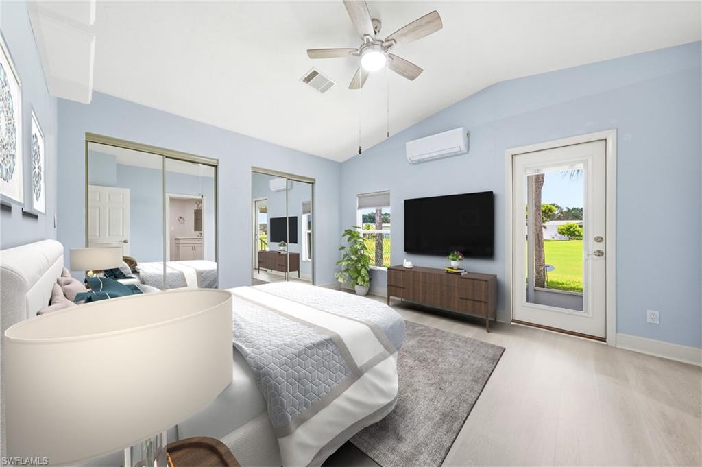 Vaulted ceiling bedroom featuring light-toned wood-finish flooring, two mirrored sliding closet doors, a ceiling fan with integrated lighting, and a glass-paneled exterior door